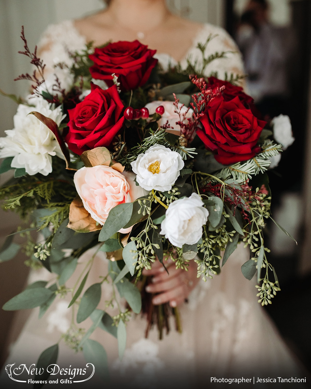 A Cascading bouquet filled with wintergreens, Vibrant Red Roses, Red Berries, White accenting flowers, pinecones, and a touch of Gold dipped wide greenery